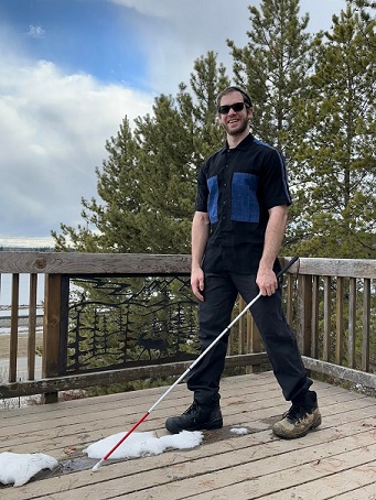 Evan standing on deck with mountains behind him