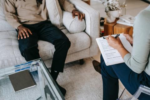 woman holding clipboard, man on couch