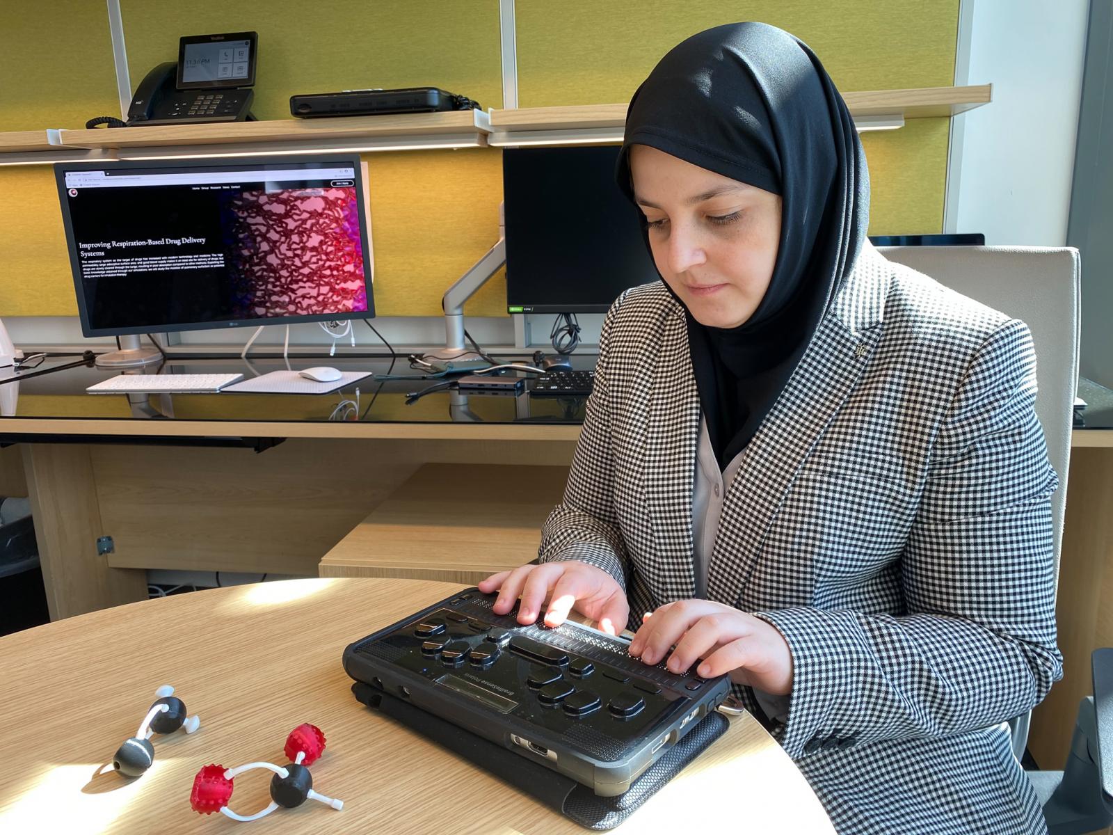 Mona Minkara using braille display