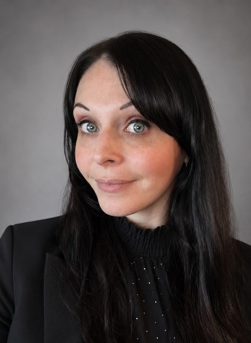 Headshot of Stephanie. Stephanie is wearing a black blouse and is smiling.